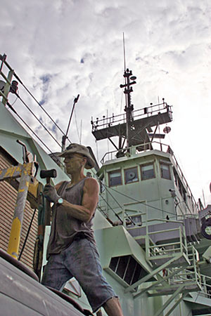 Seaman Kevin Threadgold repairs a part on the boat used to launch and recover the submersible Alvin. The boat is kept on the ship�s stern, in view of the top lab, mast, and radar antennae.