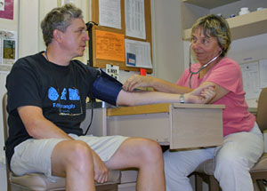 Mitzi Crane, chief mate and medical officer on Atlantis, checks researcher Yuri Rzhanvov�s blood pressure in the ship�s hospital. Mitzi said she is most often called to bandage cuts, treat heat-related illnesses, assist seasick people, remove foreign objects from eyes, and soothe fingers pinched in doors. She also has 24-hour phone access to doctors in the United States for more serious health problems.