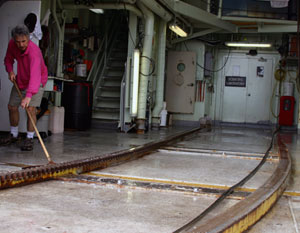 Geologist Dan Fornari washes down the hangar on the fantail, where Alvin is maintained and stored at night while its batteries recharge. (Photo by Amy Nevala)