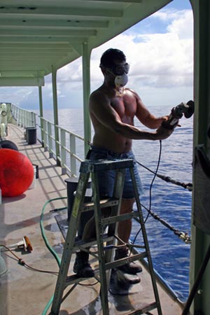 4. Seaman Raul Martinez fights the never-ending battle against rust on the decks by sanding rough spots then applying protective paint. (Photo by Amy Nevala)