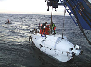Alvin enters the water while the swimmers steady the lift line. The Avon keeps an eye out for any loose equipment and watches out for the safety of the swimmers. 