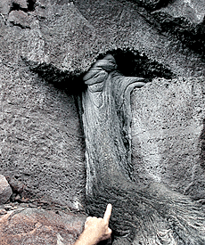  Greg Kurras’s finger pointing to the lava flow that has traveled through the small lava tube in the cliff face. Scale across photo is about 1 meter. Photo by Dan Fornari, WHOI. 