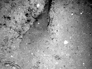 This little sediment pond is right in the middle of the lava flow (at about 0445 hrs on the tow track). When part of the lava flow is lower than the rest, sediment slides from the surface of the lava flow and piles up in the depression. However, we can see from the fissure, which is about 50 centimeters wide, that the sediment is not very thick.  